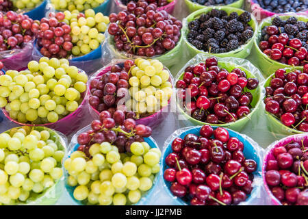 Fresco su vite verde e rosso uva senza semi e ciliegie sul display nel mercato degli agricoltori Foto Stock