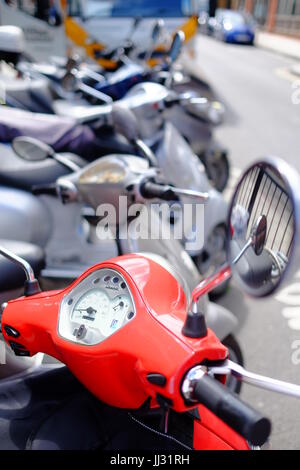 Un rosso scooter Vespa parcheggiata in una fila di scooter vicino la stazione di Euston, London Foto Stock