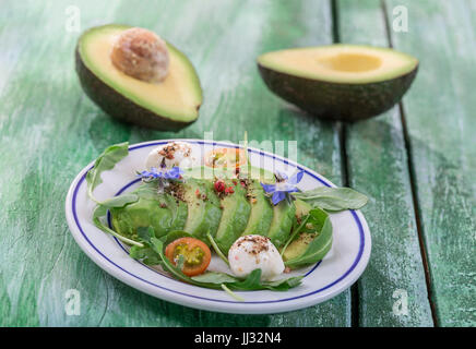 Toast con avocado e salmone affumicato sulla piastra bianca sul vecchio di legno verde scheda craked con dimezzato avocado sul retro Foto Stock