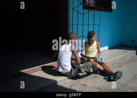 Due ragazzi giocare a carte lungo simon bolivar all Avana, Cuba Foto Stock