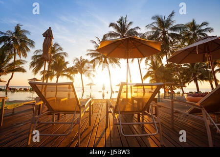 Due sedie a sdraio vicino alla piscina al tramonto nella spiaggia di lusso hotel sull isola tropicale Foto Stock
