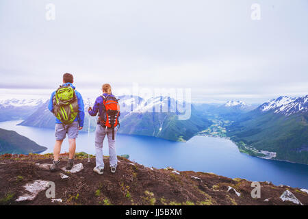 Paio di escursionisti sulla cima della montagna, gruppo di viaggiatori con lo zaino in spalla in viaggio in Norvegia fiordi, persone guardando il bellissimo paesaggio panoramico Foto Stock