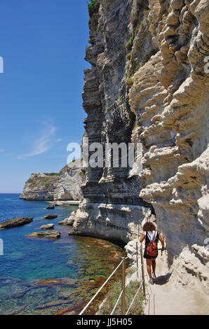 Giovane turista femminile sullo stretto sentiero intagliato nella roccia sotto Bonifacio Foto Stock