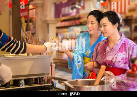 Tradizionale Giapponese pancake essendo servita sul cibo in stallo sulla cucina aperta in Asakusa, Giappone. Asian Girls mano di dessert e bellezza da indossare il kimono assortiti Foto Stock