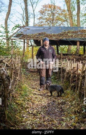 Mark Eccleston e il suo cane Bertie. Egli è un ex segnalatore ferroviario, chi noleggia sette acri di bosco rigenerati a Telford, Shropshire. Regno Unito Foto Stock