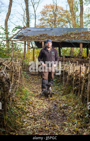 Mark Eccleston e il suo cane Bertie. Egli è un ex segnalatore ferroviario, chi noleggia sette acri di bosco rigenerati a Telford, Shropshire. Regno Unito Foto Stock