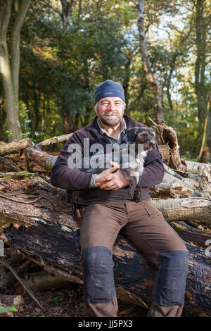 Mark Eccleston e il suo cane Bertie. Egli è un ex segnalatore ferroviario, chi noleggia sette acri di bosco rigenerati a Telford, Shropshire. Regno Unito Foto Stock