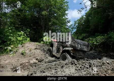 Un uomo russo guida un quad fuoristrada in un'area montuosa fangosa nel lato sud-orientale dell'isola di Sakhalin, nell'Oceano Pacifico. Russia Foto Stock