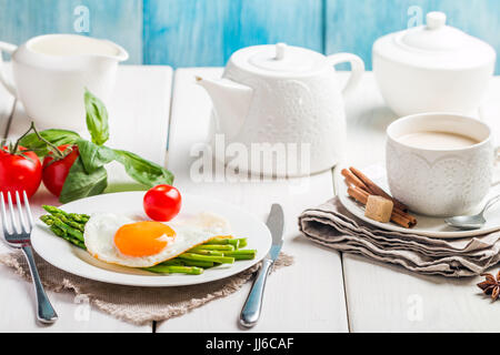 Uova strapazzate con asparagi servita su bianco sullo sfondo di legno per la colazione Foto Stock