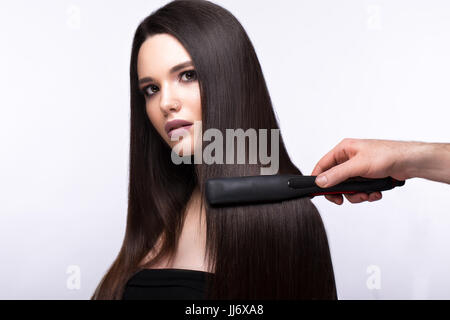 Bella bruna ragazza con una superficie perfettamente liscia capelli, curling e classic per il make-up. Bellezza viso Foto Stock