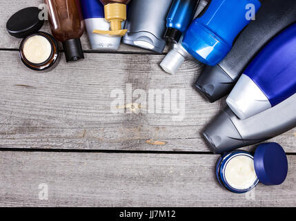 Mens cosmetici sfondo. Vari prodotti cosmetici per uomo stabiliti come cornice semicircolare su vecchie tavole di legno. Spazio di copia Foto Stock