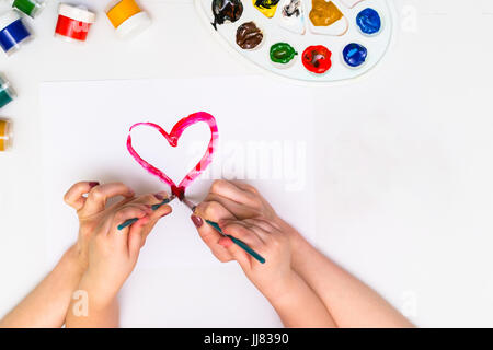 Bambino con le mani in mano di verniciatura di un cuore Foto Stock