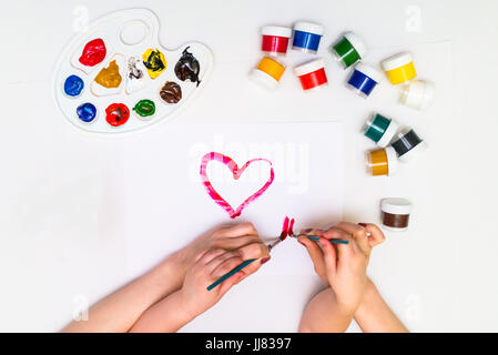 Bambino con le mani in mano di verniciatura di un cuore Foto Stock