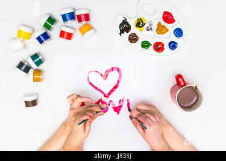 Bambino con le mani in mano di verniciatura di un cuore Foto Stock