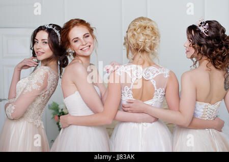 Sposa nel salone per matrimoni. Quattro bellissima ragazza sono in ogni altra delle armi. Indietro, close-up gonne di pizzo Foto Stock