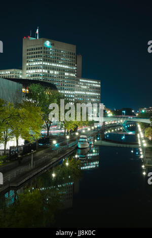 Una scena notturna nel centro cittadino di Ottawa, Canada mostra barche ormeggiate lungo il Rideau Canal, la difesa nazionale uffici e la Convenzione di Ottawa Centre Foto Stock