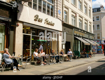 La Gente seduta sul marciapiede al di fuori dei Bar Italia, Frith Street, Soho, Londra Foto Stock