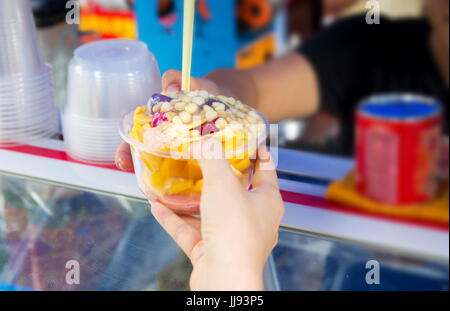 Acquisto femmina insalata di frutta sulla strada del mercato Foto Stock