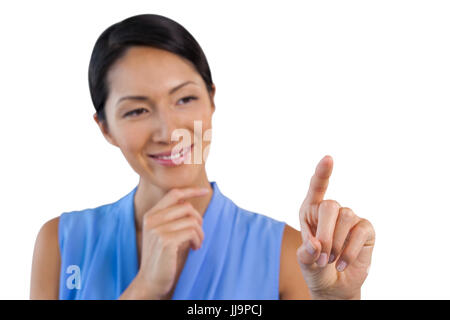 Imprenditrice sorridente con la mano sul mento interfaccia toccante contro uno sfondo bianco Foto Stock