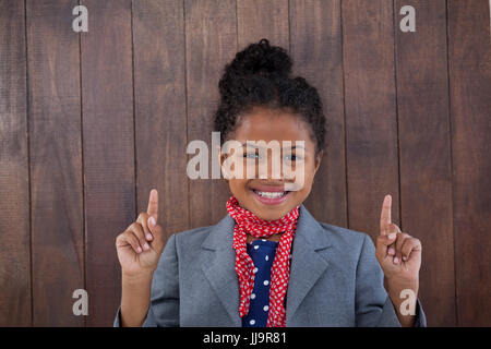 Ritratto di ragazza sorridente fingendo come imprenditrice rivolto verso l'alto mentre in piedi contro uno sfondo bianco Foto Stock