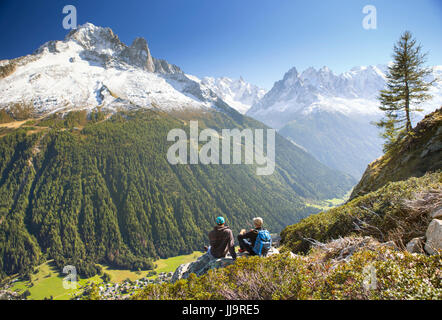 Due escursionisti sono godendo della vista sul Mont Blanc montagne mentre riposa sul Tour du Mont Blanc. Essi si trovano sul loro modo di Lac Blanc, sopra la valle di Chamonix. Foto Stock