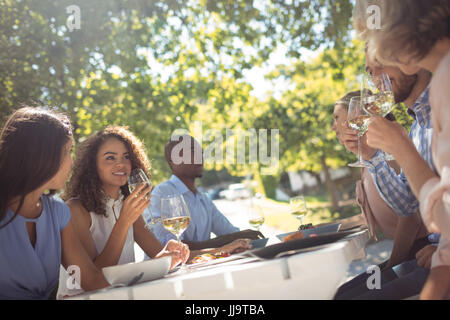 Happy amici interagire mentre avente un bicchiere di vino nel ristorante Foto Stock