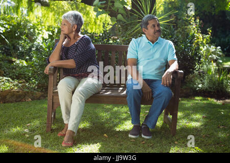 Coppia senior sostenendo seduti sulla panchina del parco Foto Stock