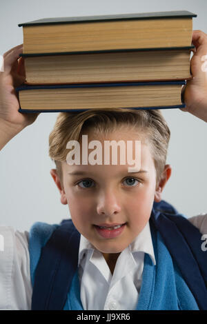 Ritratto di scolaro tenendo il suo libro sulla sua testa Foto Stock