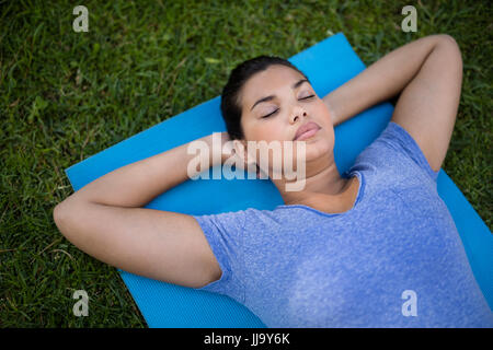 Angolo di alta vista di giovani formatori rilassante esercizio sul tappetino in park Foto Stock