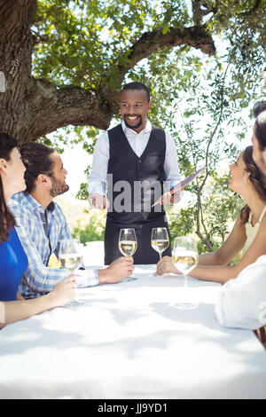 Gli amici mettendo fine al cameriere del ristorante Foto Stock