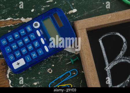 Close-up di calcolatrice e lavagna su tavola Foto Stock