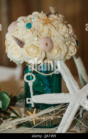 Carino, divertente, fatti a mano. Spiaggia Oceano a tema Matrimonio Ricevimento decorazioni. Parte Centrotavola con bouquet floreali, stelle marine, e chiave Foto Stock