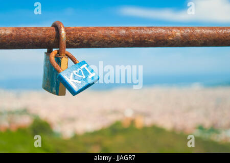 Lucchetti sul rusty bar con vista offuscata di Barcellona dal Tibidabo su soleggiate giornate estive, Barcellona, in Catalogna, Spagna Foto Stock
