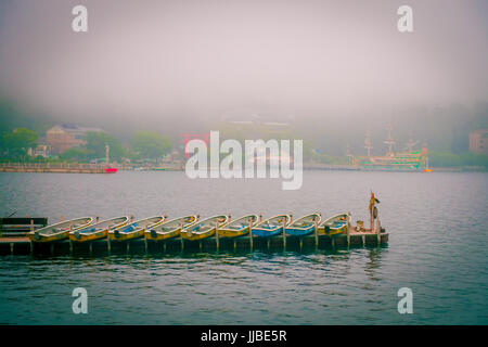 HAKONE, Giappone - Luglio 02, 2017: barche da pesca e rosso Porta Torii di Sacrario di Hakone sul lago Ashi su nebbioso giorno. Foto Stock