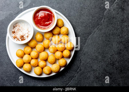 Patate fritte sfera, crocettes sulla piastra bianca con salsa di pomodoro, ardesia sfondo, vista dall'alto. Foto Stock