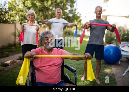 Portatori di handicap senior uomo con nastro con gli amici mentre si esercita in posizione di parcheggio Foto Stock