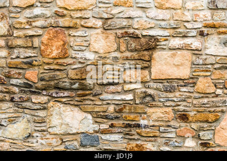 La parte dei vecchi ma bel muro di pietra. Texture di sfondo, struttura profonda, andamento irregolare. Foto Stock