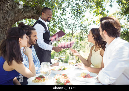 Gli amici mettendo fine al cameriere del ristorante Foto Stock