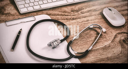 Angolo di alta vista di uno stetoscopio con appunti con la tastiera e il mouse sul tavolo Foto Stock