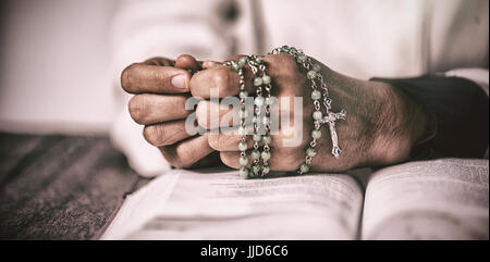 La donna le mani a pregare con il santo Rosario e la bibbia sul tavolo di legno Foto Stock