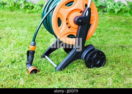 Avvolto il tubo flessibile da giardino sulla bobina, erba sfondo Foto Stock