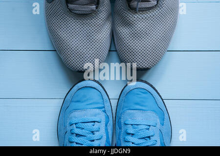 Due coppie di sport sneakers punta-punta. l uomo, grigio e donna blu. minore idoneità per due. su sfondo blu. top vista aerea Foto Stock