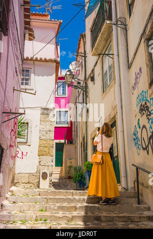 Donna città turistica, vista posteriore di una giovane donna di scattare una foto di una strada nel colorato quartiere di Alfama della città di Lisbona, Portogallo. Foto Stock