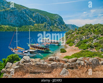 Vista di tre imbarcazioni turistiche a Camellia isola nel Mare Egeo da muro medievale rovine con montagne in background, Marmaris Turchia Foto Stock