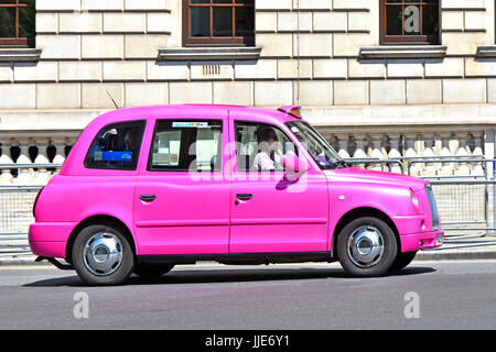 Taxi di Londra e tassista donna al lavoro in una giornata estiva di giugno alla guida di un luminoso taxi rosa a noleggio in Parliament Square Westminster Londra Inghilterra Regno Unito Foto Stock