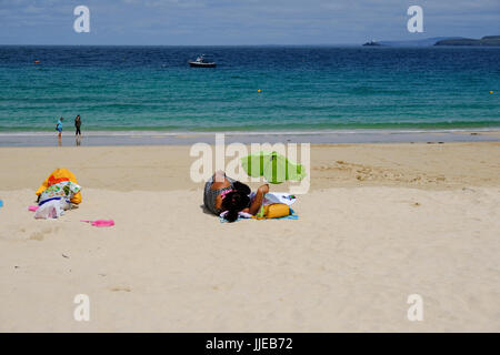 Donna sdraiata sulla spiaggia a prendere il sole St Ives, Cornwall Foto Stock