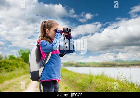 Giovane ragazza a guardare la terra attraverso il binocolo Foto Stock