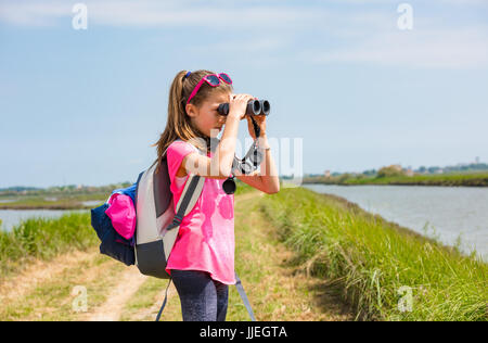 Giovane ragazza a guardare il parco attraverso il binocolo Foto Stock