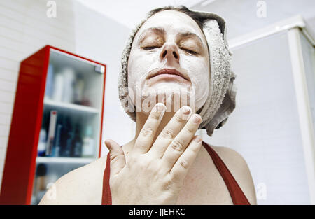 Giovane donna mettendo in creme per il viso, dettaglio di bellezza e cura del corpo Foto Stock