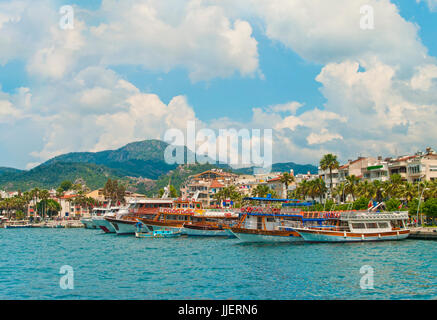 Vista delle imbarcazioni turistiche a Marmaris waterfront promenade sulla soleggiata giornata estiva con il blu del cielo e le montagne a sfondo, Turchia Foto Stock